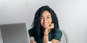 happy ethnic woman sitting at table with laptop