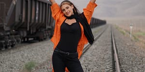 a woman holding black inflatable number balloons standing on railroad track