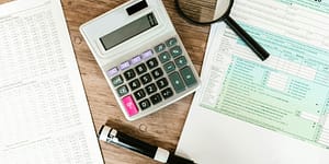 gray calculator and black magnifying glass on brown wooden surface